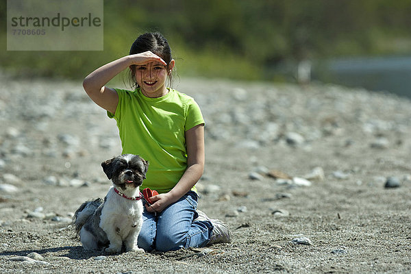 Mädchen sitzend mit Hund im Feld