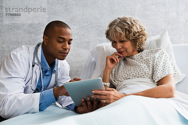 Arzt zeigt dem Patienten digitale Tablette im Krankenhaus