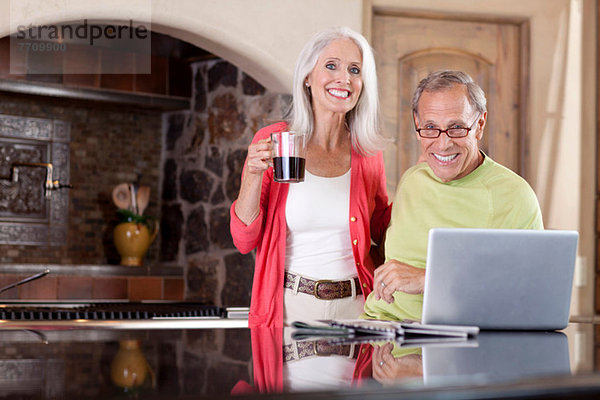 Älteres Paar mit Laptop beim Frühstück