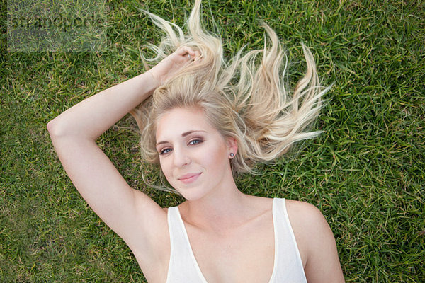 Lächelnde Frau im Gras liegend
