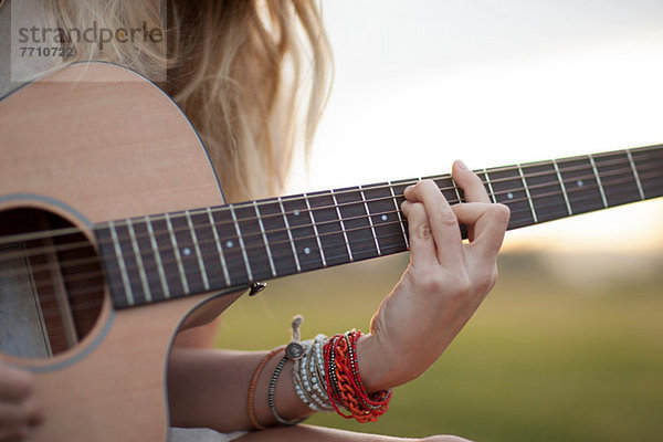 Frau spielt Gitarre im Gras