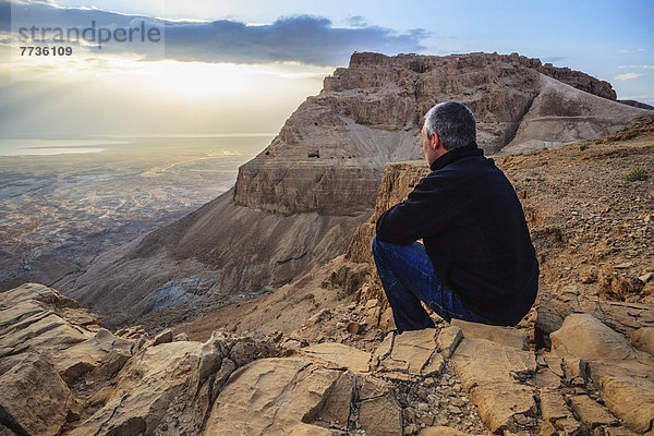 Felsbrocken Mann sitzend über Wüste hinaussehen