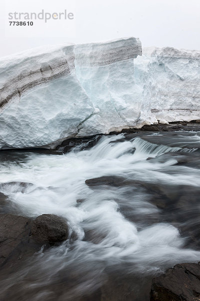 Ein kleiner Wasserfall entspringt unter einer dicken Eisschicht