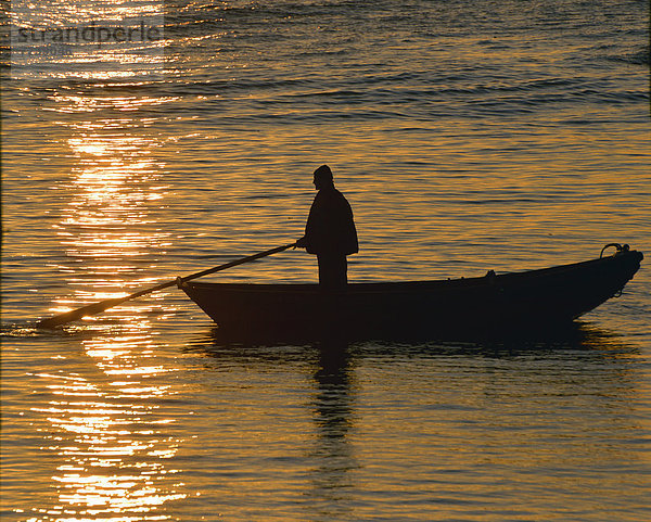 Ein Mann in einem Boot  bei Sonnenuntergang