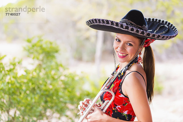 USA  Texas  Young woman holding trumpet  smiling  portrait