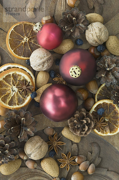 Weihnachtskugeln mit getrockneten Orangenscheiben  Schlehdorn  Walnüssen  Haselnüssen  Mandeln und Tannenzapfen auf dem Tisch