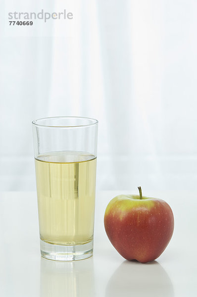 Glas Apfelsaft neben Apfel auf weißem Hintergrund  Nahaufnahme