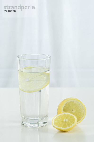 Glas Mineralwasser mit Zitrone auf weißem Hintergrund  Nahaufnahme