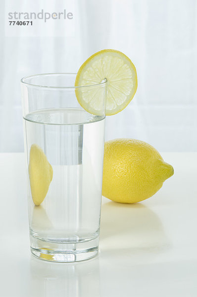 Glas Mineralwasser mit Zitrone auf weißem Hintergrund  Nahaufnahme