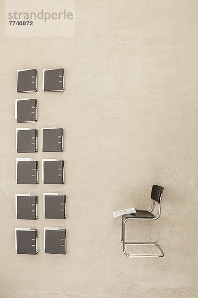 Bürostuhl mit Ordner auf beigefarbenem Hintergrund