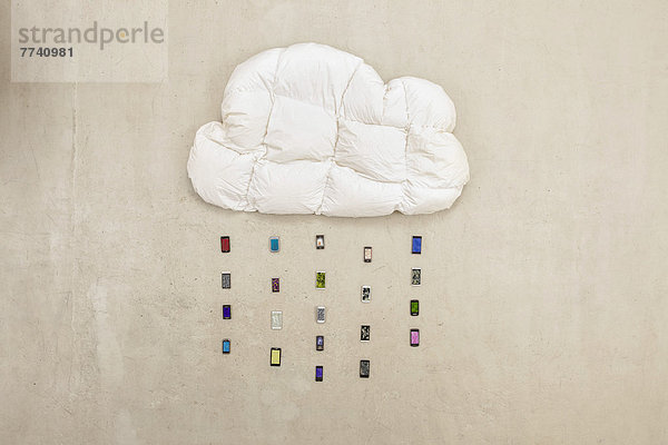 Wolkenförmiges Kissen mit Mobiltelefonen  die Regen auf beigen Hintergrund bilden.