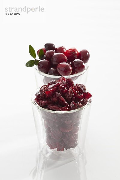 Glas frische und getrocknete Cranberries auf weißem Hintergrund  Nahaufnahme