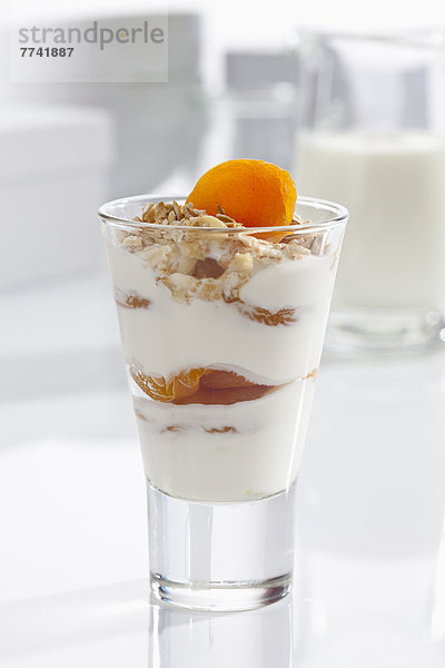 Glas Joghurt mit Müsli  Obst und Cornflakes auf weißem Hintergrund  Nahaufnahme