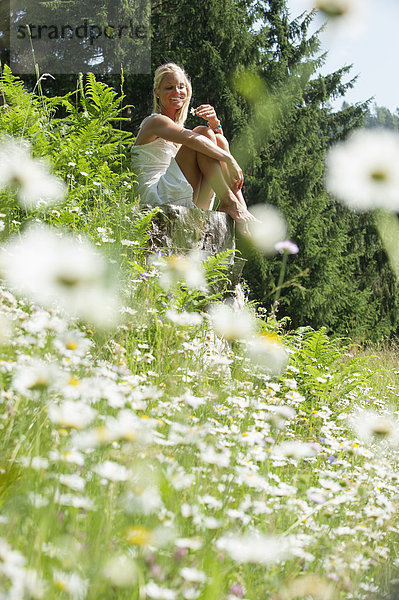 Österreich  Salzburg  Mittlere erwachsene Frau mit Blumen auf der Wiese  lächelnd