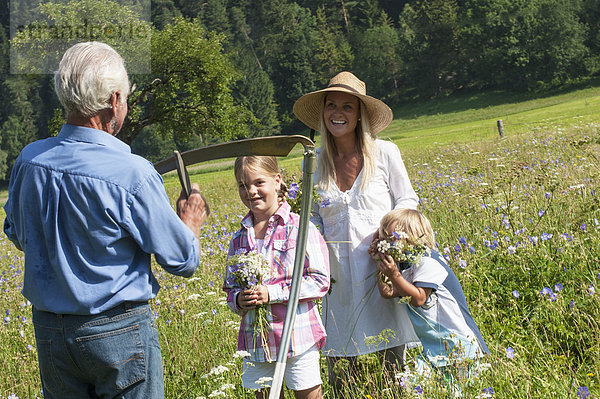 Deutschland  Salzburg  Bauer und Familie auf der Sommerwiese  lächelnd