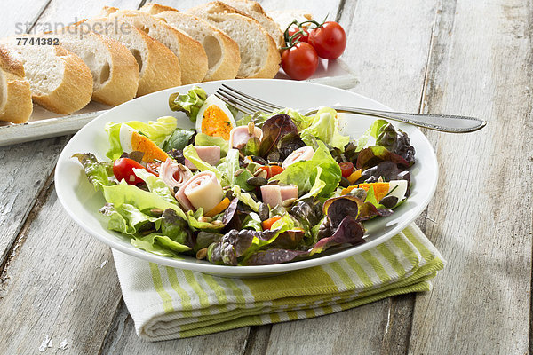 Salatteller mit Schinken und Käse und Brot im Tablett auf dem Tisch  Nahaufnahme