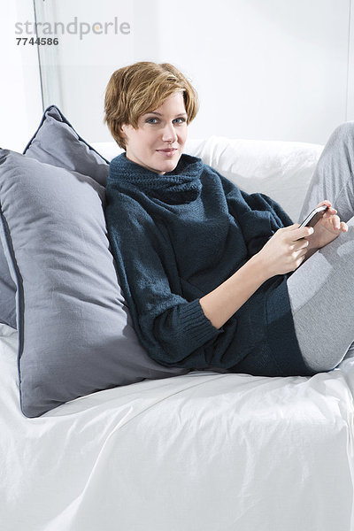 Junge Frau mit Handy auf der Couch  Portrait