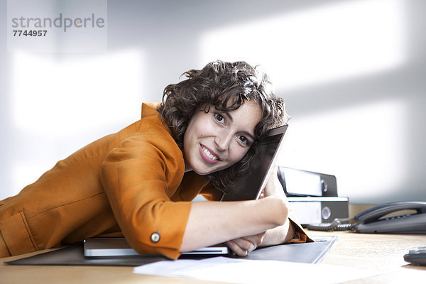 Geschäftsfrau umarmt Laptop im Büro  lächelnd  Portrait