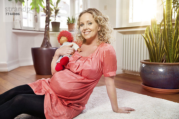 Porträt einer schwangeren Frau mit Puppe  lächelnd