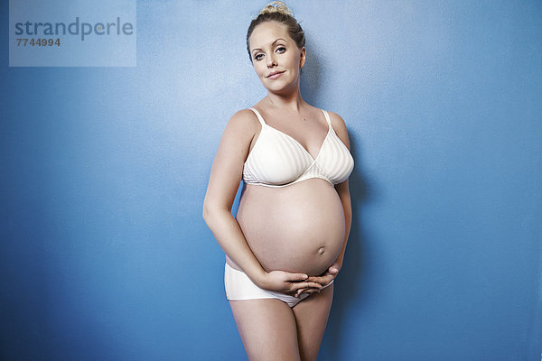 Schwangere Frau hält ihren Bauch  lächelnd  Portrait