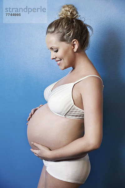 Schwangere Frau hält ihren Bauch  lächelnd