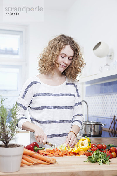 Junge Frau beim Gemüsehacken in der Küche