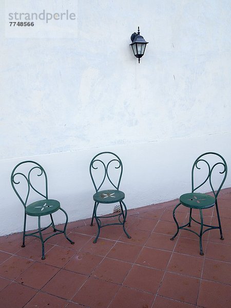 Drei Stühle auf Fliesenboden im Freien