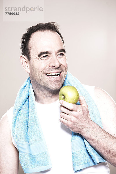Lachender Mann mit Handtuch um den Hals hält einen Apfel  Portrait
