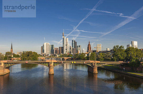 Skyline von Frankfurt im Morgenlicht  mit der Ignatz-Bubis-Brücke und dem Main vorne