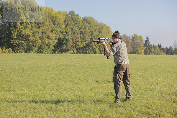 Jäger wartet mit der Waffe im Anschlag auf Wild