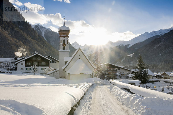 Verschneite Kirche und Sonne