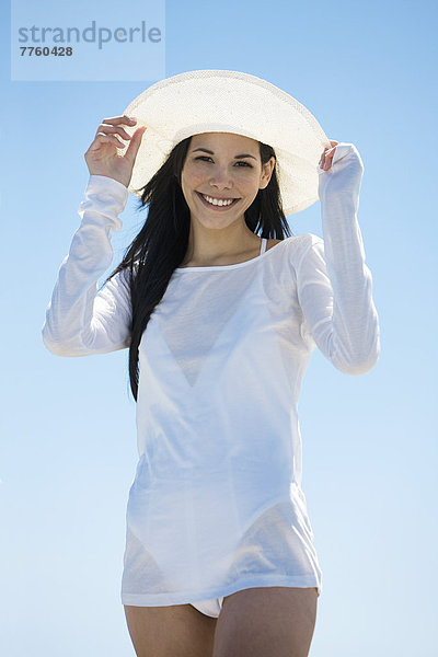 Junge Frau lächelt vor der Kamera  weißer Hut