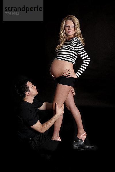 Mann sitzend  Beine einer schwangeren Frau haltend