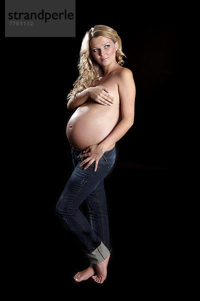 Oben-ohne schwangere Frau mit Händen  die die Brust bedecken.