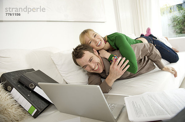 Lächelndes Paar auf Sofa  Laptop-Computer