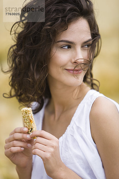 Porträt einer jungen Frau mit Müsliriegel