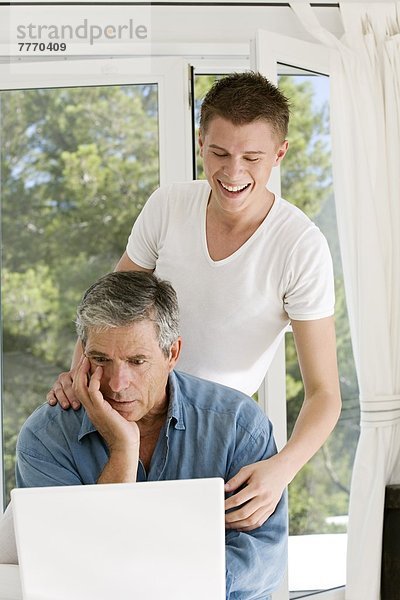 Senior Mann ein junger Mann zu Hause  mit Laptop