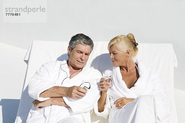 Erwachsenes Paar im Bademantel  auf der Terrasse sitzend
