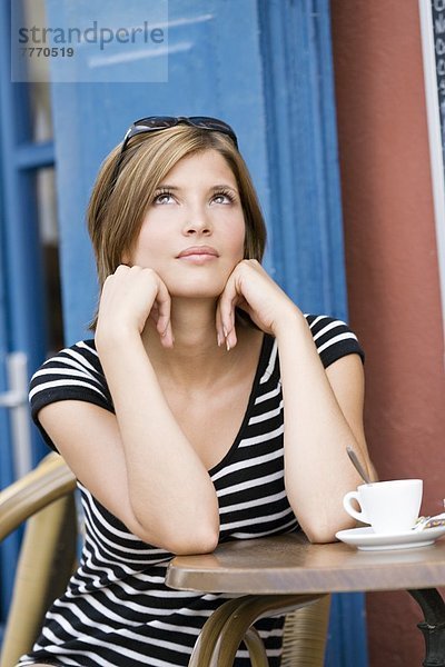Junge Frau  die auf der Terrasse des Cafés sitzt.