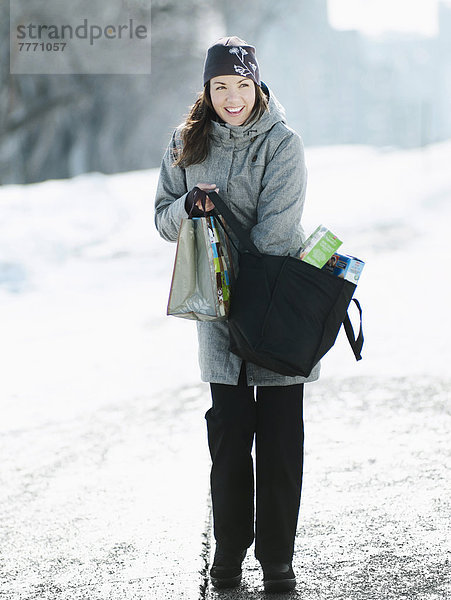 Junge Frau mit Einkaufstaschen im verschneiten Pfad