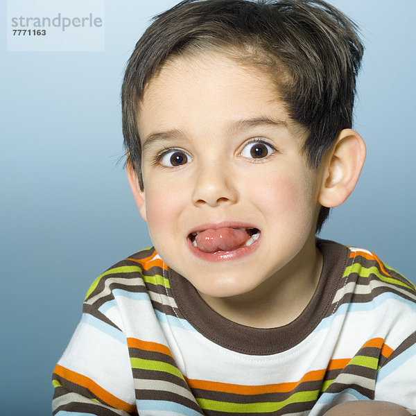 Porträt eines kleinen Jungen  der die Zunge herausstreckt.