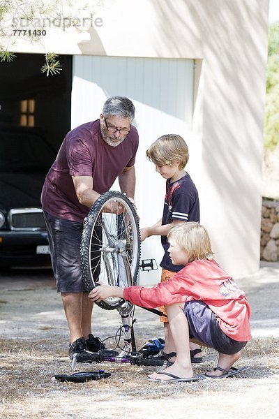 Mann und Kinder reparieren Fahrrad