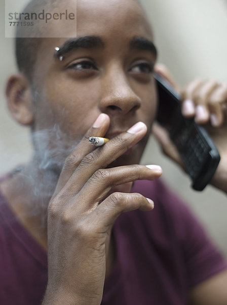 Teenager-Junge raucht beim Telefonieren