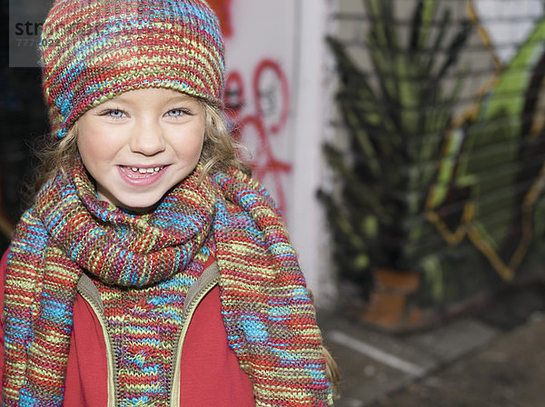 Kleines Mädchen lächelnd auf der Straße  Wollmütze und Schal