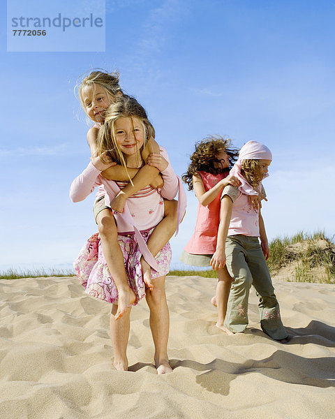 Vier kleine Mädchen spielen am Strand