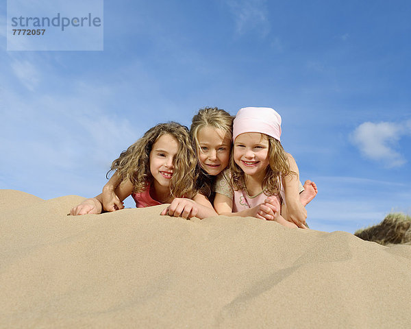 Drei kleine Mädchen am Strand liegend