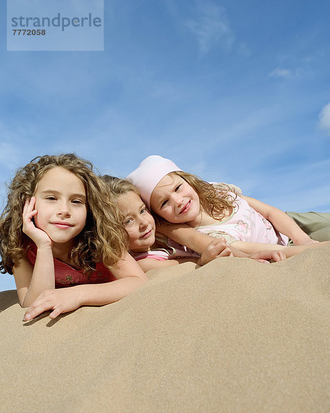 Drei kleine Mädchen am Strand liegend