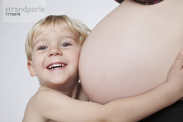 Kind mit Kopf auf dem Bauch einer schwangeren Frau