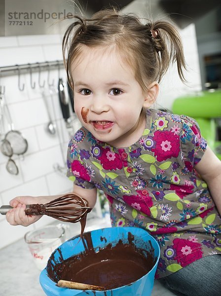 Kleines Mädchen spielt mit Schokolade in der Küche