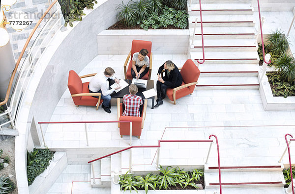 Hohe Blickwinkel auf Geschäftsleute  die am Tisch in der Bürolobby diskutieren